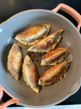 Pan-fried Mt Tam dumplings cooking until golden and crispy, combining creamy triple cream cheese with a savory filling for a rich and flavorful appetizer.