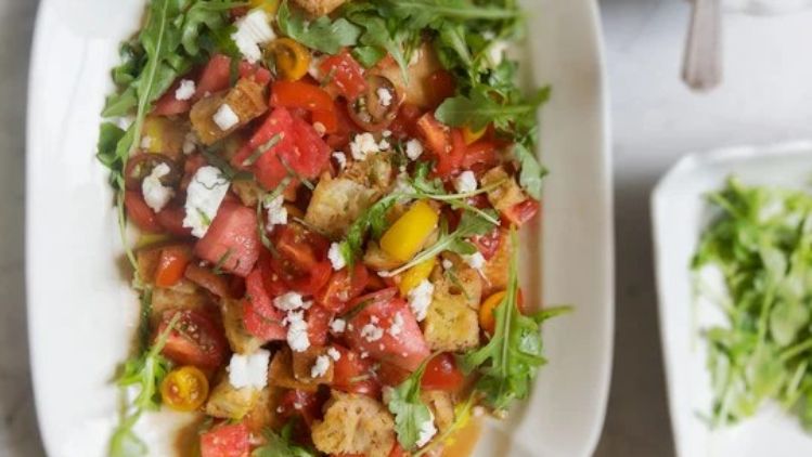 Watermelon and feta panzanella salad with juicy tomatoes, peppery arugula, and toasted bread, creating a refreshing balance of sweet and savory flavors.