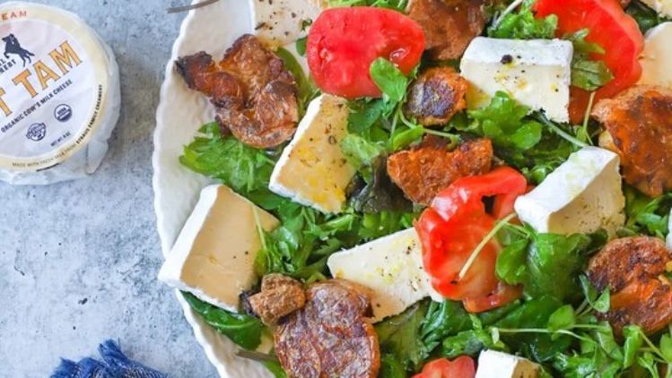 Mt Tam triple cream cheese salad with crispy roasted potatoes, fresh greens, and ripe tomatoes, offering a perfect balance of creamy, crunchy, and refreshing flavors.