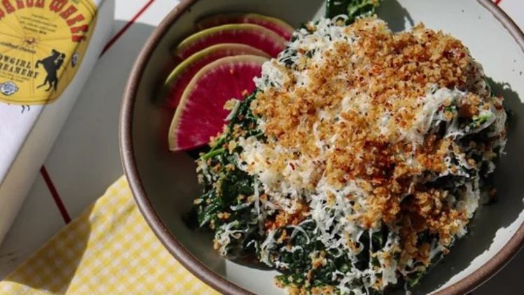 Kale Caesar salad topped with Wagon Wheel cheese, crispy breadcrumbs, and shaved radishes, delivering a rich, savory twist on a classic favorite.