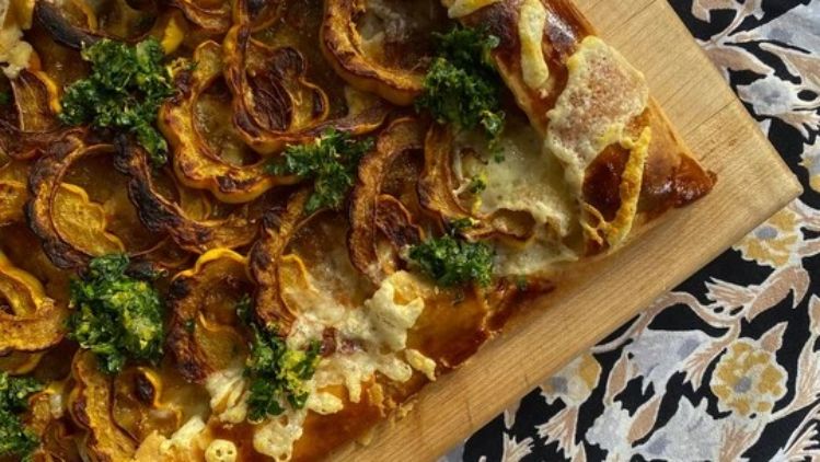 Savory squash galette topped with melted artisan cheese, roasted delicata squash, and fresh herb pesto on a flaky golden crust.