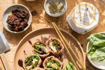 Prosciutto-wrapped Mt Tam rotolo filled with fresh basil, leafy greens, and sun-dried tomatoes, served with a rich balsamic glaze for an elegant appetizer.