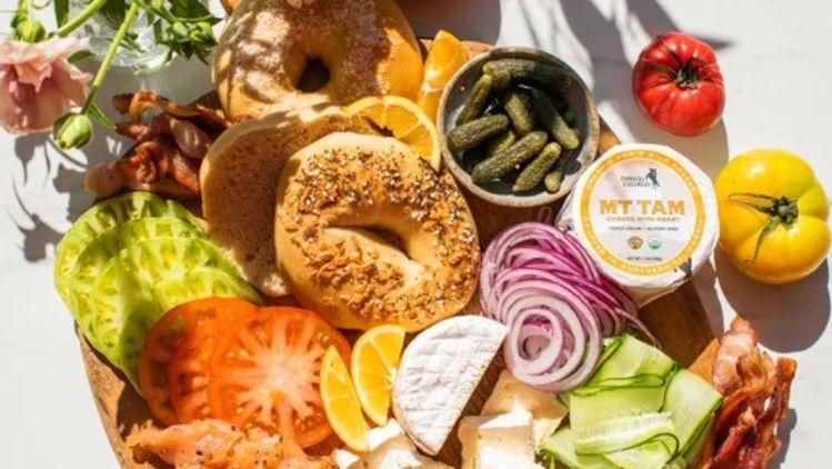 Bagel and lox charcuterie board featuring Mt Tam triple cream cheese, smoked salmon, fresh vegetables, red onion, capers, and artisan bagels for an elevated brunch spread.