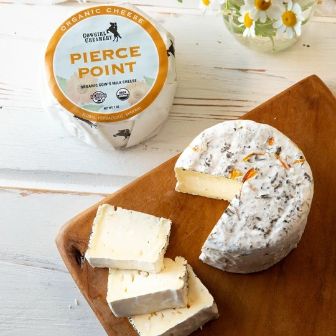 Pierce Point organic cheese from Cowgirl Creamery, featuring a creamy interior and a bloomy rind infused with wild herbs and edible flowers.