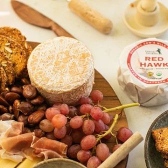 Artisan cheese board featuring Red Hawk cheese, cured meats, grapes, nuts, and crisp seeded crackers, perfect for entertaining and gourmet gatherings.