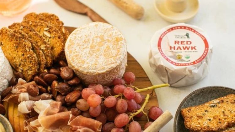 Artisan cheese board featuring Red Hawk cheese, cured meats, grapes, nuts, and crisp seeded crackers, perfect for entertaining and gourmet gatherings.