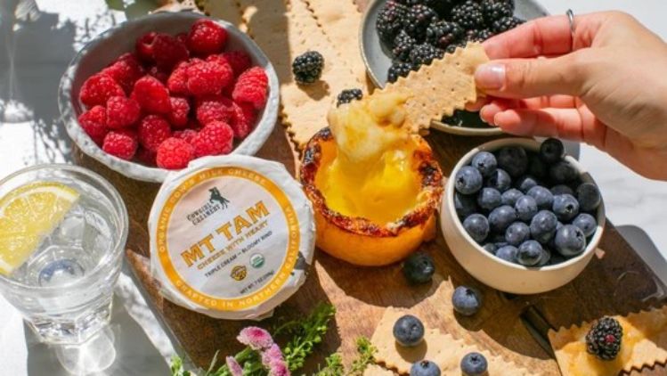 Brûléed Mt Tam triple cream cheese served with fresh berries and crackers, creating an elegant sweet-and-savory appetizer with a rich caramelized topping.