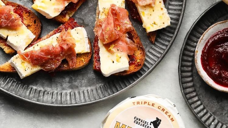 Mt Tam, prosciutto, and fig jam crostini served on toasted sourdough, combining creamy triple cream cheese, savory cured ham, and sweet fig preserves.