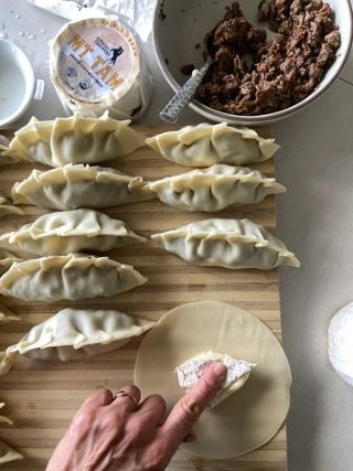 Mt Tam-filled dumplings being assembled by hand, combining savory filling and creamy triple cream cheese for a rich and flavorful appetizer.