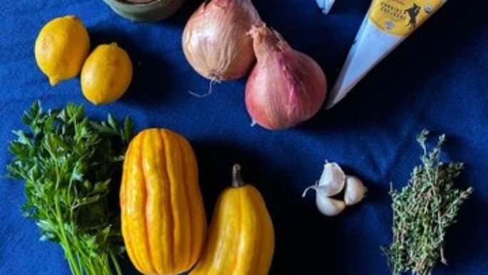 Fresh ingredients for a roasted delicata squash galette, featuring artisan cheese, shallots, garlic, herbs, lemon, and seasonal squash.