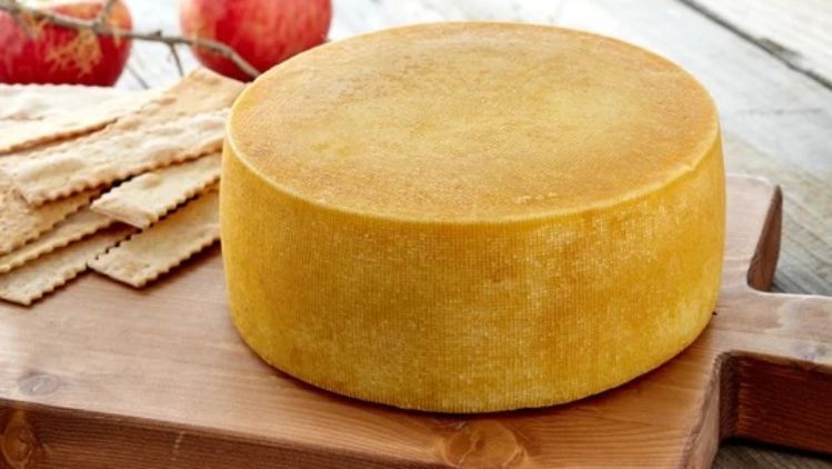 Hop Along artisan cheese wheel displayed on a wooden board, showcasing its natural golden rind and handcrafted farmstead character.