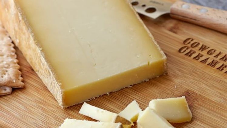 Wagon Wheel artisan cheese served on a wooden board, showcasing its firm texture, natural rind, and rich handcrafted character.