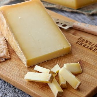 Wagon Wheel artisan cheese served on a wooden board, showcasing its firm texture, natural rind, and rich handcrafted character.